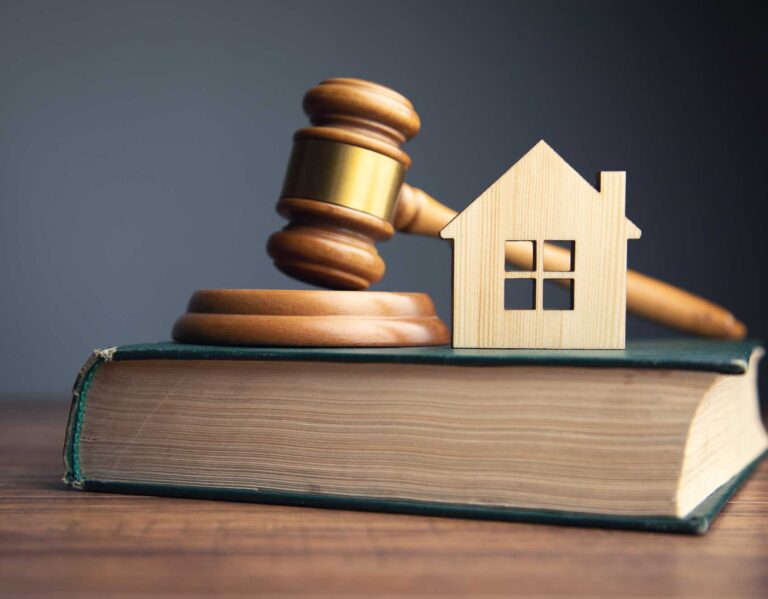 Book of Law with a Judge's gavel and and a wooden house representing Real estate law