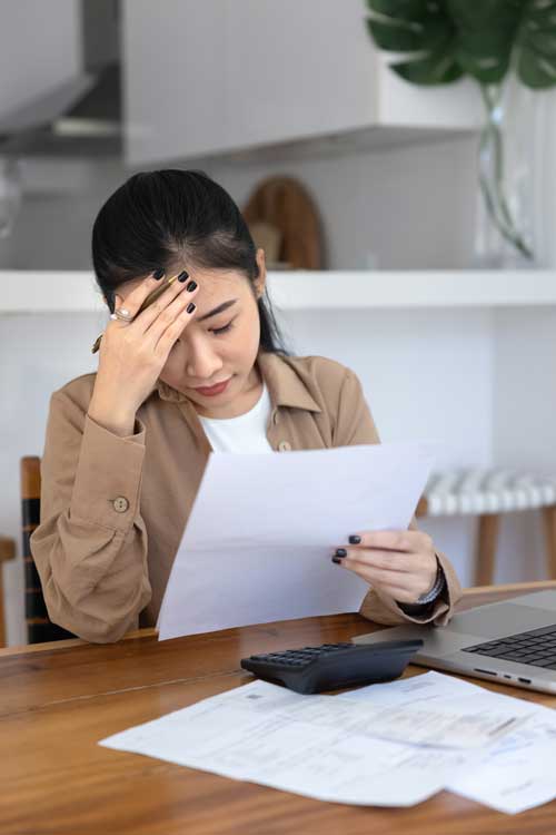 Defensa-Contra-Demandas-Civiles Asian/Hispanic woman looking concerned while viewing legal documents at her computer